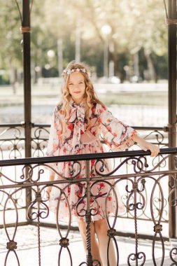 Gülümseyen sarışın kız yaz bahçesinde poz veriyor. Çiçek takan