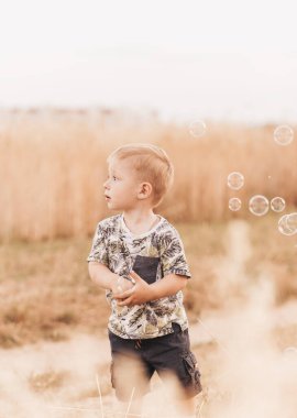 Küçük çocuk yazın doğada oynar ve yürür. Mutlu bir çocukluk. Pozitif duygular