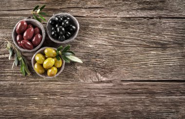 Ahşap masada yeşil, siyah ve kırmızı zeytinyağı. Üst görünüm