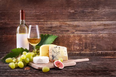Ahşap zemin üzerinde üzüm, peynir ve beyaz şarap kompozisyonu. Boşluğu kopyala