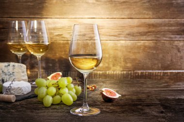 Ahşap zemin üzerinde üzüm, peynir ve beyaz şarap kompozisyonu. Boşluğu kopyala