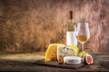 Ahşap zemin üzerinde üzüm, peynir ve beyaz şarap kompozisyonu. Boşluğu kopyala