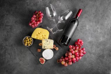 Üzüm, peynir ve şaraptan oluşan koyu taş bir zemin. Üst görünüm