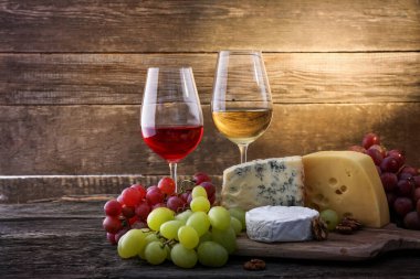 Ahşap arka planda üzüm, şarap ve peynir.