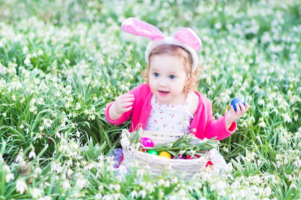 Girl wearing bunny ears playing with Easter eggs — Stock Photo, Image