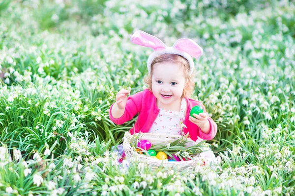 Meisje dragen bunny oren spelen met Pasen eieren — Stockfoto