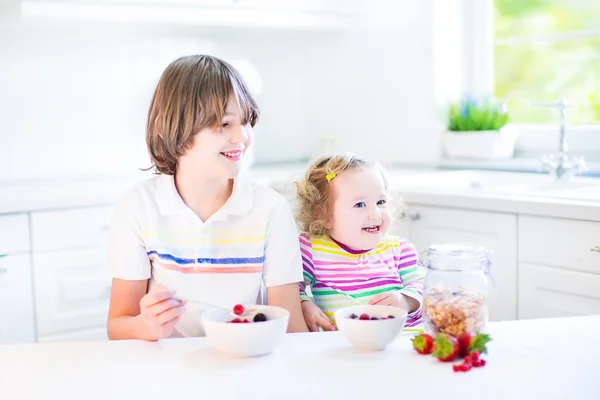 Niño y hermana tomando frutas y cereales con fresa para el desayuno —  Fotos de Stock