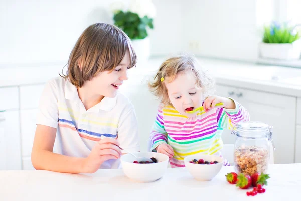 Junge und Schwester mit Obst und Müsli mit Erdbeere zum Frühstück — Stockfoto