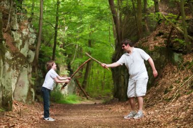 Baba ve oğul uzun bir yürüyüş üzerinde sopa ile oynama