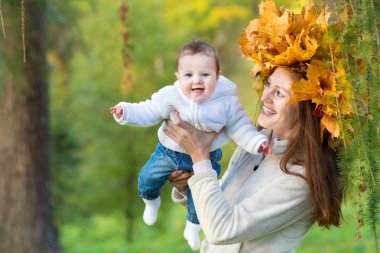 Anne kız tatlı bebek tutan maple leaf çelenk içinde
