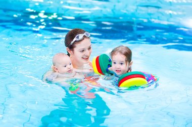 Young active mother having fun in a swimming pool with two kids clipart