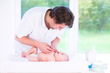 Genç baba oğlunun yeni doğan bebek bezi değiştirme