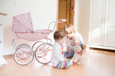 birlikte bir beyaz odada oynayan genç bir çocuk ve bebek kız