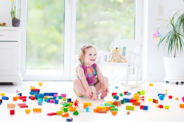 Toddler girl playing with colorful blocks clipart
