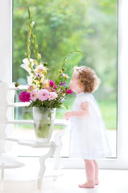 büyük bir pencere yanında taze çiçek kokan bebek kız
