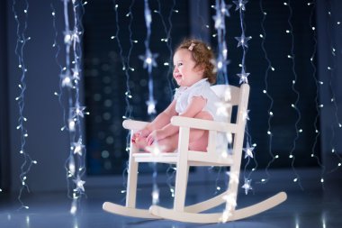 Toddler kızın rahatlatıcı beyaz bir sallanan sandalyede