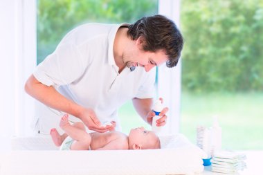 Genç baba oğlunun yeni doğan bebek bezi değiştirme