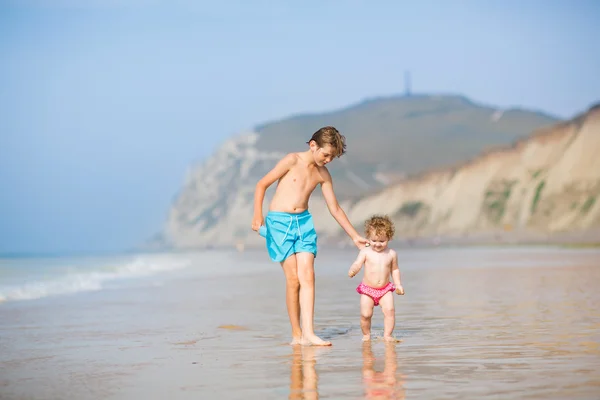 Twee kinderen lopen op een mooi strand — Stockfoto
