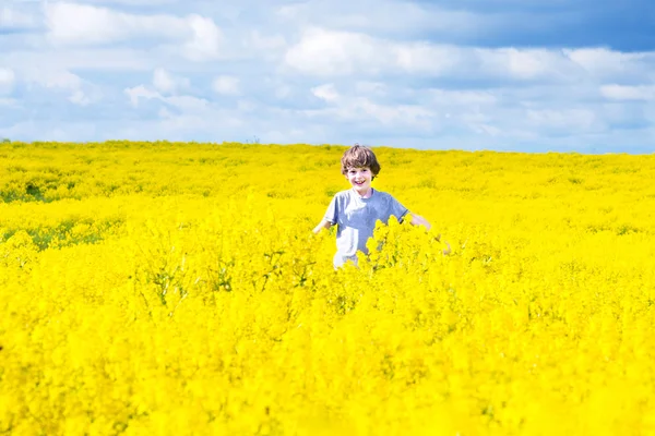 Child running in a field of yellow flowers — Stock Photo, Image