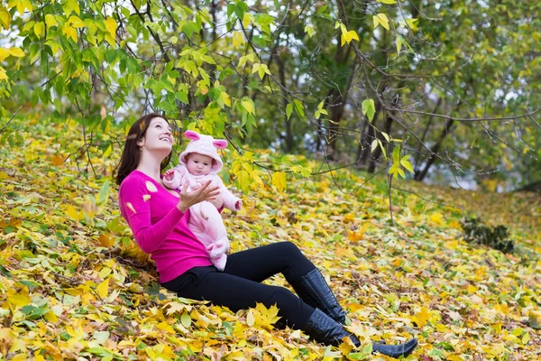 Mother holding her baby daughter under a tree — Stock Photo, Image