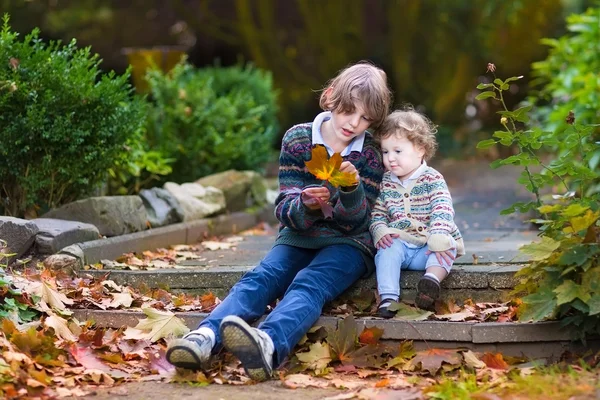 Brother and his little baby sister in a beautiful autumn park — Stock Photo, Image