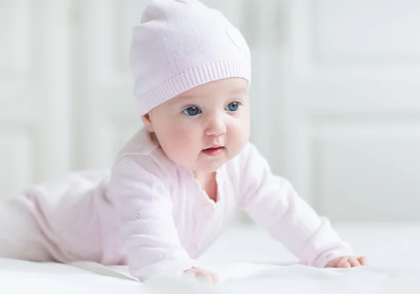 Beautiful baby girl with big blue eyes on a white blanket playing on her tummy — Stock Photo, Image