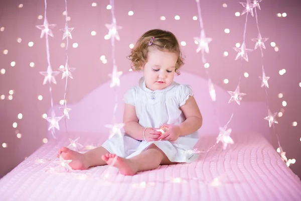 Barn flicka som leker på en vit säng — Stockfoto