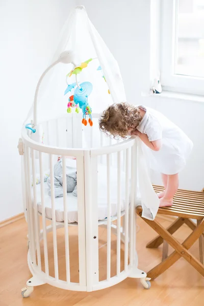 Toddler girl looking at her newborn baby brother — Stock Photo, Image