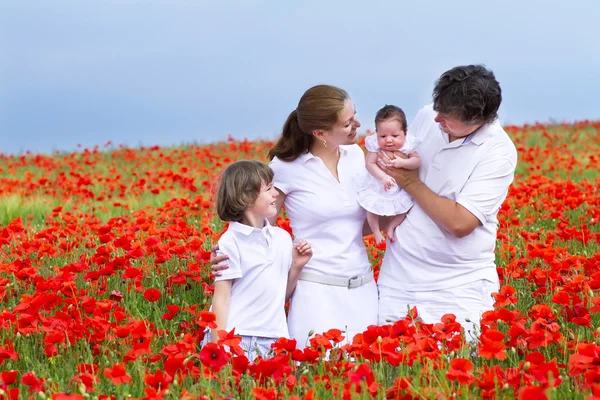Familia con un hijo y una hija recién nacida en un campo rojo — Foto de Stock