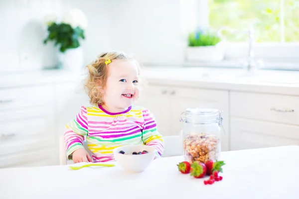 Toddler dziewczynka śniadanie sok do picia i jedzenia corn flakes z truskawkami — Zdjęcie stockowe