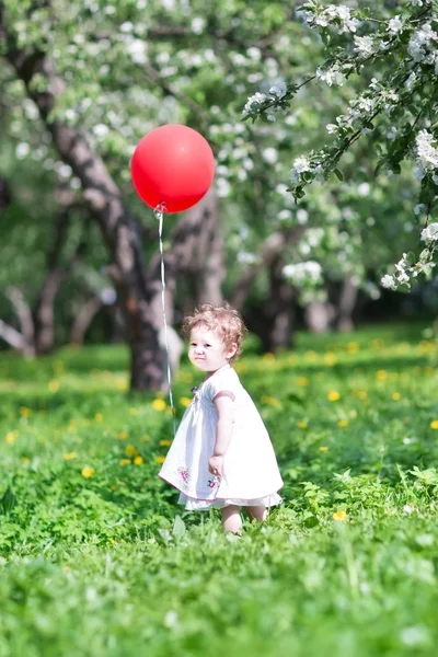 Meisje van de baby spelen met een grote rode ballon — Stockfoto