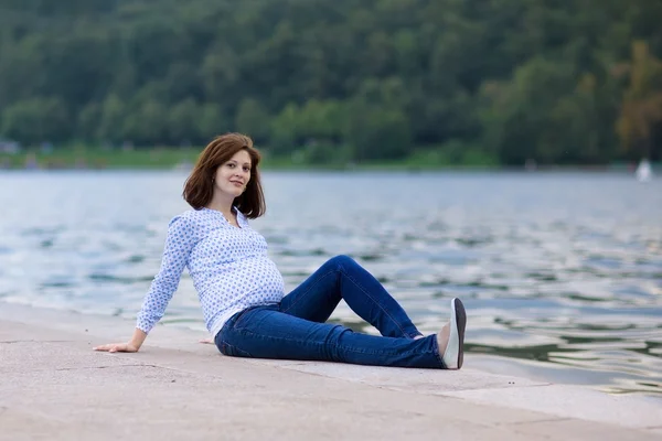 Pregnant woman relaxing at a river shore — Stock Photo, Image