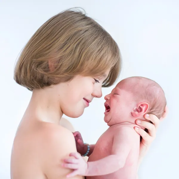 Teenage boy playing with his newborn baby brother — Stock Photo, Image