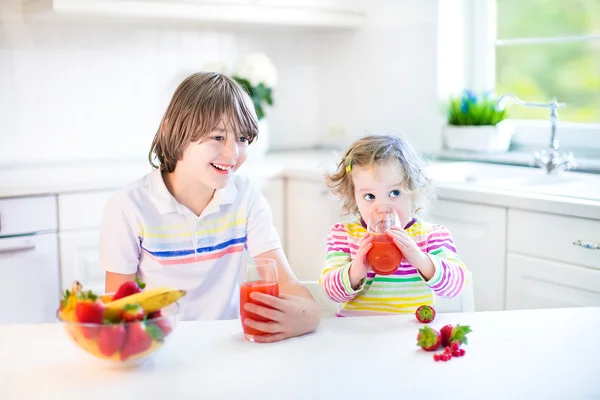Tonåring pojke och hans syster med frukt och flingor med jordgubbar till frukost — Stockfoto
