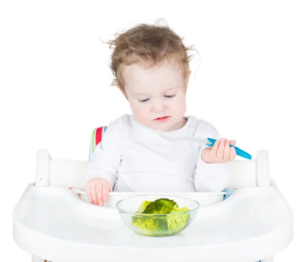 Niño en una trona blanca comiendo sus verduras —  Fotos de Stock