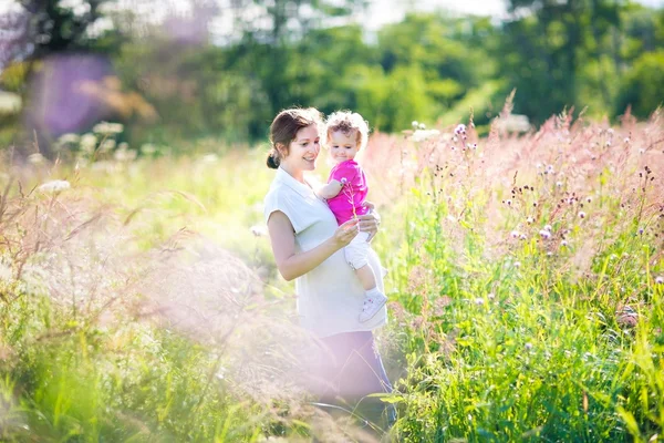 Mutter hält ihre müde kleine Tochter in einem Park — Stockfoto