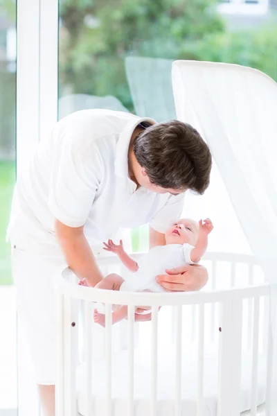 Junger lächelnder Vater legt sein neugeborenes Baby hin — Stockfoto