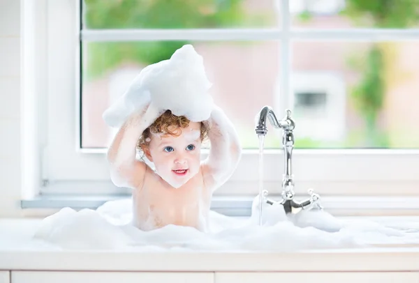 Дитяча дівчинка з великими блакитними очима грає у ванній — стокове фото