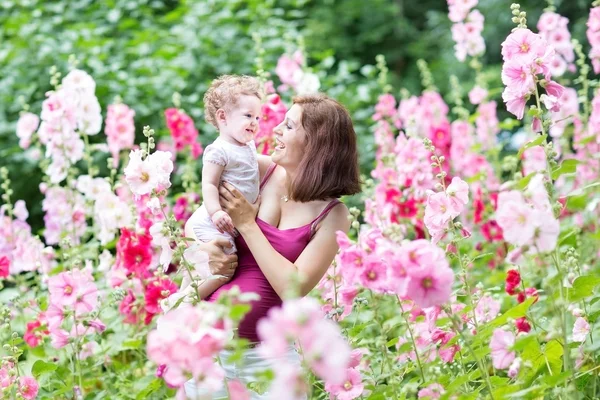 Pregnant mother playing with her baby daughter in a in a blooming garden — Stock Photo, Image