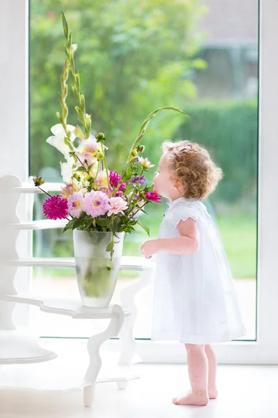 Baby girl smelling beautiful flowers — Stock Photo, Image