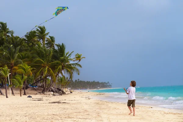 Pojke leker med en drake på en strand — Stockfoto