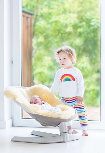 Toddler girl playing with her newborn baby brother — Stock Photo, Image