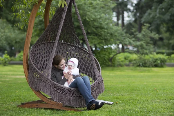 Mãe relaxante com uma menina em uma rede — Fotografia de Stock