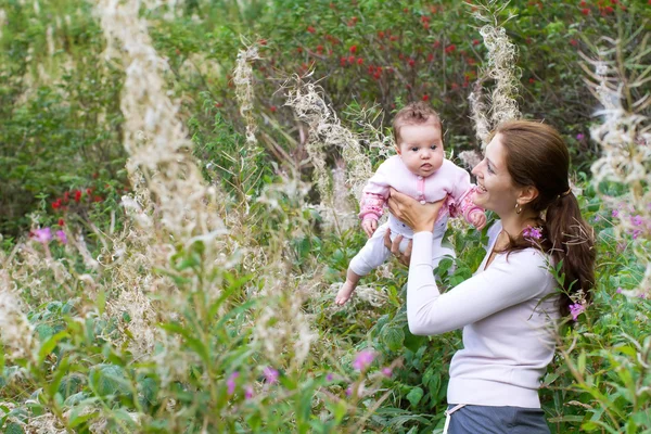 Donna che tiene il suo bambino in un campo di fiori colorati — Foto Stock