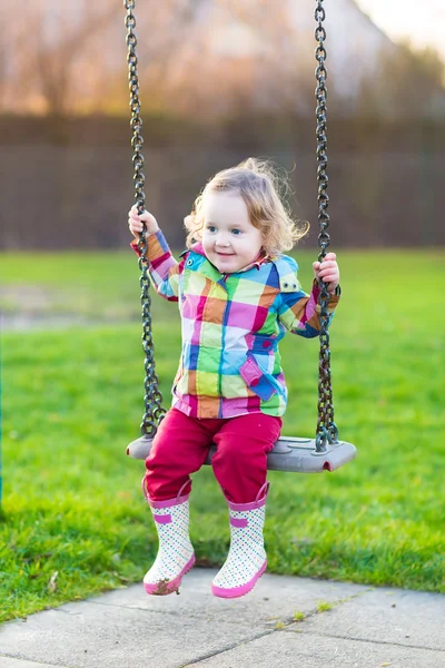 Meisje van de baby plezier op een schommel in de tuin — Stockfoto