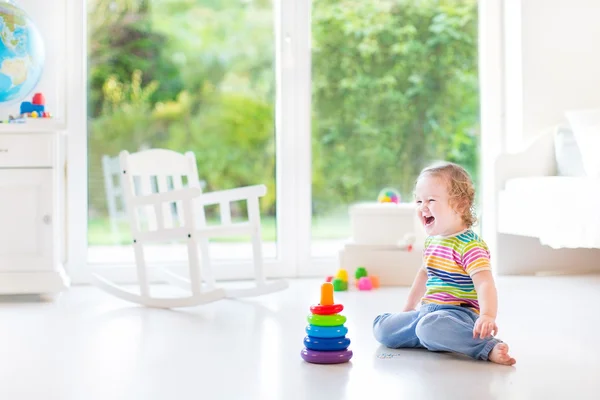 Маленькая девочка играет с красочной пирамидой — стоковое фото