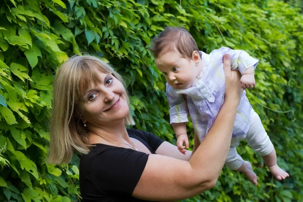 Senhora segurando um bebê em um jardim — Fotografia de Stock
