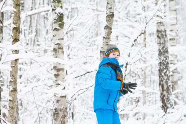 Rapaz bonito andando em uma floresta nevada — Fotografia de Stock