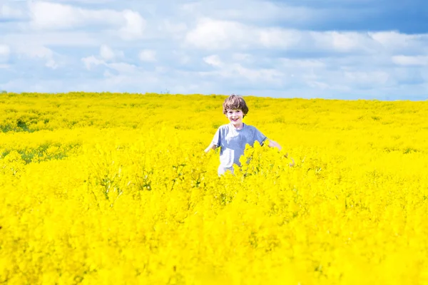 Bambino che corre in un campo di fiori gialli — Foto Stock