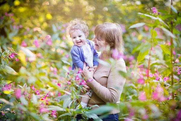 Mujer jugando con una niña riendo en un jardín —  Fotos de Stock